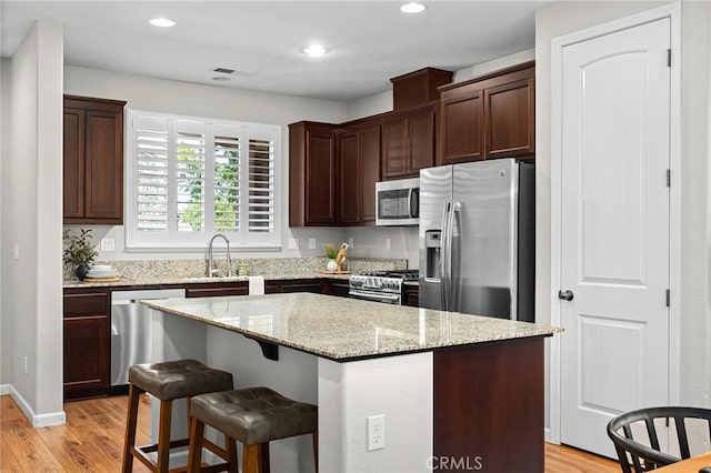3274 Tinker Creek Way, Chico, CA 95973 - kitchen featuring appliances with stainless steel finishes, a sink, light wood-style flooring, a kitchen island, and light stone countertops