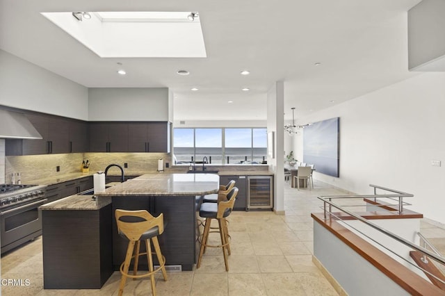 815 Mandalay Beach Rd, Oxnard, CA 93035 - kitchen featuring wine cooler, high end stainless steel range, a sink, a kitchen bar, and light stone countertops