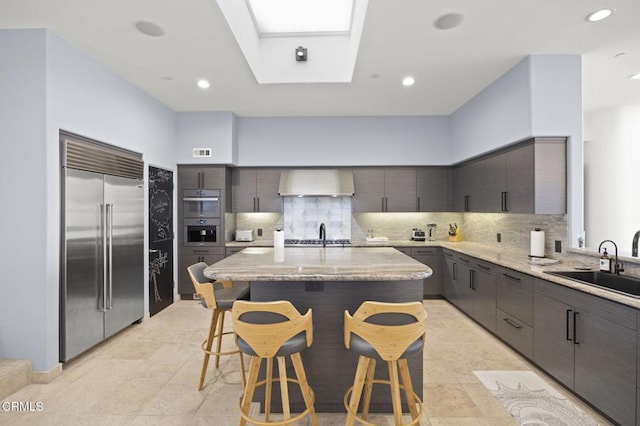 815 Mandalay Beach Rd, Oxnard, CA 93035 - kitchen featuring appliances with stainless steel finishes, a sink, wall chimney range hood, a kitchen breakfast bar, and tasteful backsplash