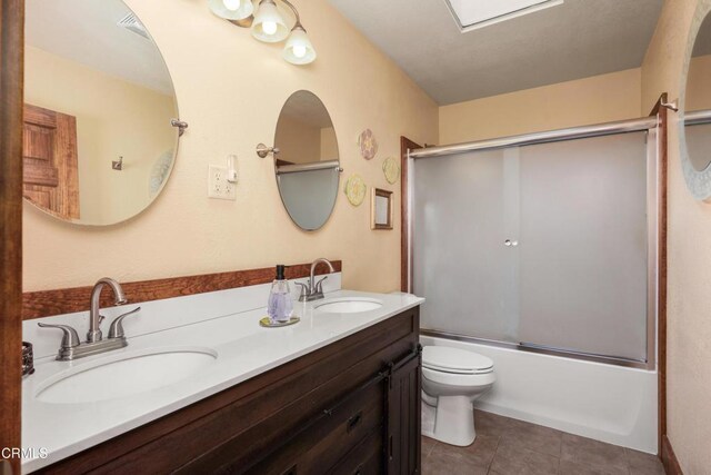 51793 Quail Ridge Rd, Oakhurst, CA 93644 - bathroom featuring double vanity, toilet, shower / bath combination with glass door, and tile patterned flooring