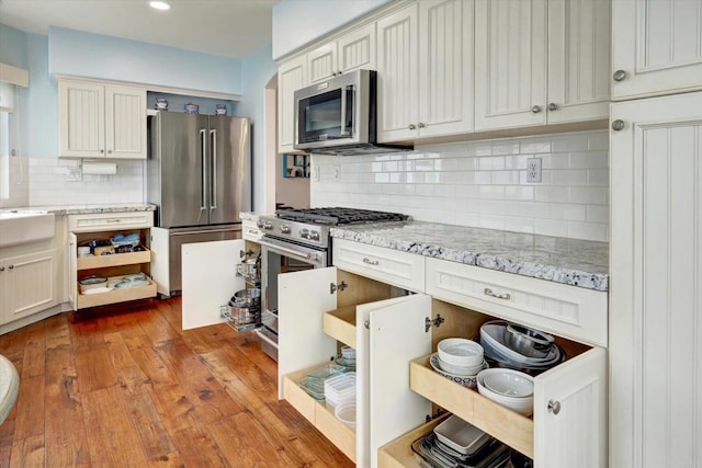 3372 Corsica Way, Oceanside, CA 92056 - kitchen with appliances with stainless steel finishes, decorative backsplash, wood finished floors, light stone counters, and recessed lighting