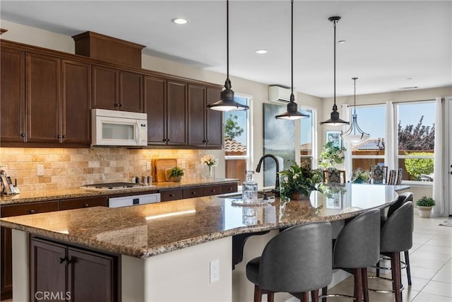 905 Romneya Ln, Santa Maria, CA 93455 - kitchen with a sink, white microwave, a kitchen island with sink, decorative backsplash, and stone counters