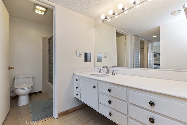277 E Alejo Rd Unit 212, Palm Springs, CA 92262 - bathroom featuring vanity, toilet, combined bath / shower with glass door, a textured ceiling, and baseboards