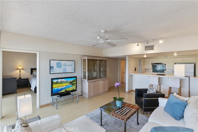 277 E Alejo Rd Unit 212, Palm Springs, CA 92262 - living room featuring a textured ceiling, light wood-type flooring, a ceiling fan, rail lighting, and baseboards