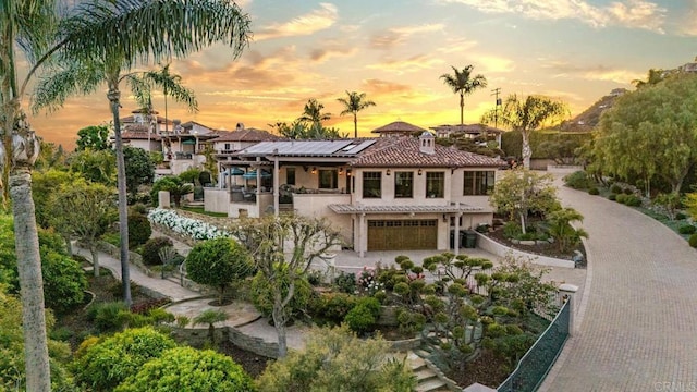 4652 Resmar Rd, La Mesa, CA 91941 - back of house at dusk with roof mounted solar panels, an attached garage, a balcony, a tile roof, and stucco siding