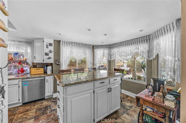 17477 Owl Tree Rd, Riverside, CA 92504 - kitchen featuring dishwasher, a textured ceiling, dark stone finish floors, a kitchen island, and plenty of natural light
