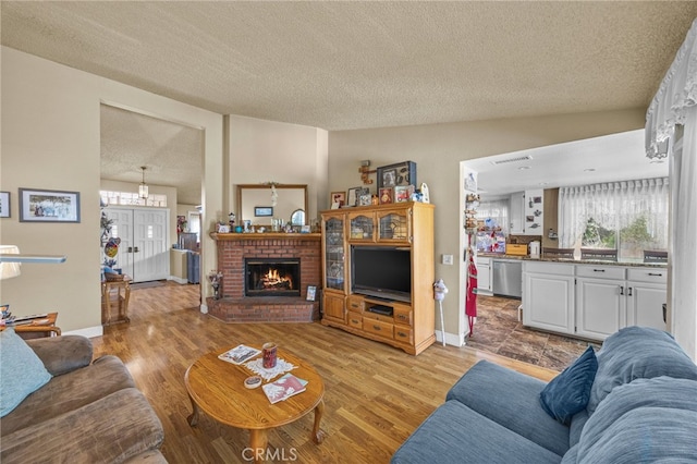 17477 Owl Tree Rd, Riverside, CA 92504 - living area featuring a textured ceiling, healthy amount of natural light, a brick fireplace, and light wood-style flooring