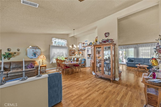 17477 Owl Tree Rd, Riverside, CA 92504 - living room with a textured ceiling, vaulted ceiling, wood finished floors, plenty of natural light, and a chandelier