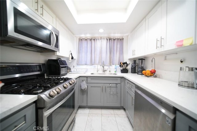 532 Venice Way Unit 8, Inglewood, CA 90302 - kitchen featuring stainless steel appliances, gray cabinets, a tray ceiling, light countertops, and light marble finish flooring