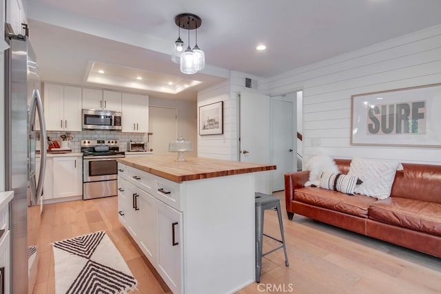 201 Todd Ct, Oceanside, CA 92054 - kitchen with stainless steel appliances, wood counters, open floor plan, a breakfast bar, and light wood-style flooring