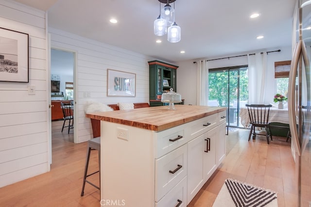 201 Todd Ct, Oceanside, CA 92054 - kitchen featuring butcher block counters, a breakfast bar, light wood finished floors, white cabinets, and decorative light fixtures