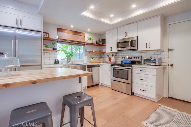 201 Todd Ct, Oceanside, CA 92054 - kitchen with appliances with stainless steel finishes, open shelves, butcher block countertops, light wood-style flooring, and a breakfast bar area