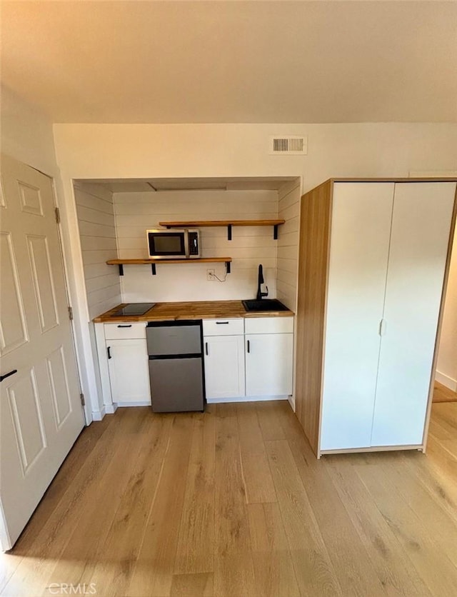 201 Todd Ct, Oceanside, CA 92054 - kitchen with refrigerator, stainless steel microwave, open shelves, light wood-style floors, and white cabinetry