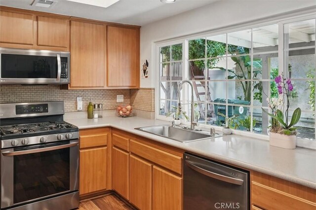 24214 Dalgo Dr, Valencia, CA 91355 - kitchen featuring stainless steel appliances, a sink, light countertops, backsplash, and light wood-style floors
