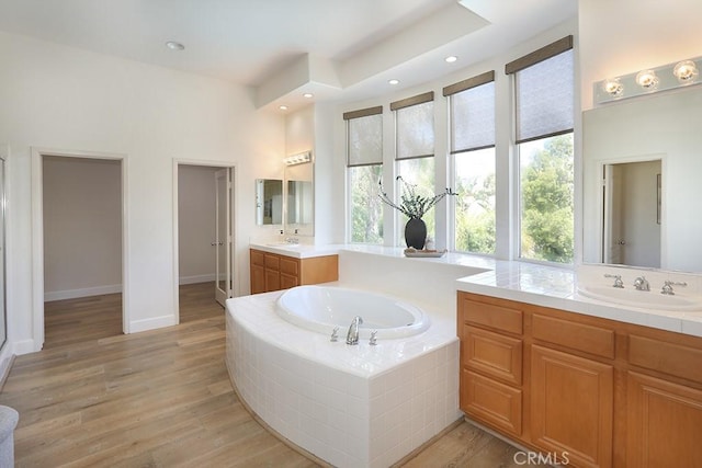 1019 N Sonora Cir, Orange, CA 92869 - bathroom with two vanities, a bath, wood finished floors, and recessed lighting