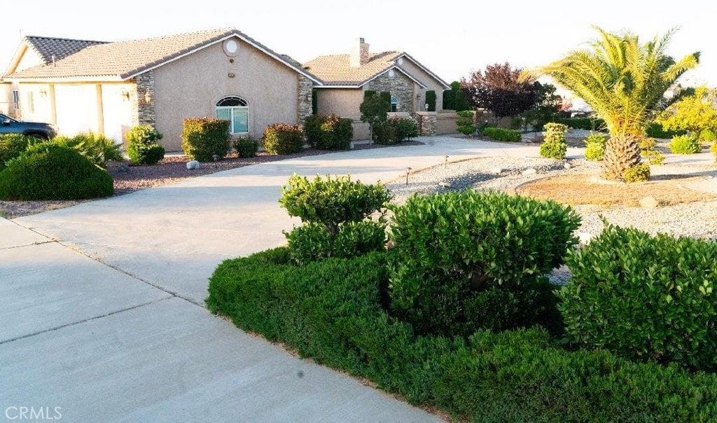 12720 Farmington St, Oak Hills, CA 92344 - view of front of property featuring stucco siding, stone siding, a chimney, and concrete driveway