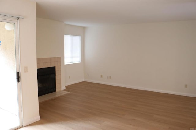 11215 Avenida De Los Lobos Unit F, Rancho Bernardo San Diego, CA 92127 - unfurnished living room with light wood finished floors, a tile fireplace, and baseboards