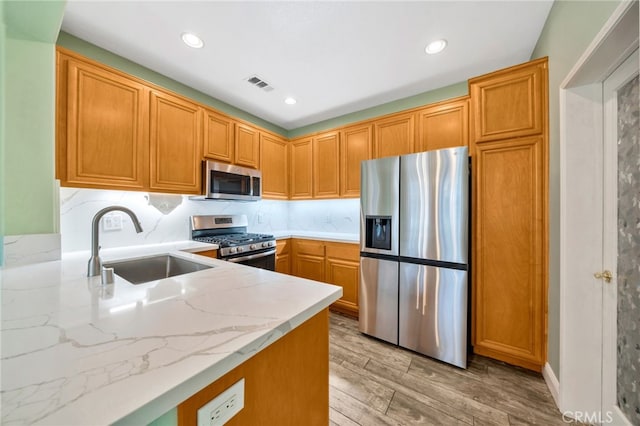 25 Ellsworth St Unit 11, Ladera Ranch, CA 92694 - kitchen featuring appliances with stainless steel finishes, a sink, light wood finished floors, recessed lighting, and light stone counters