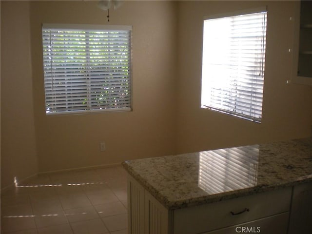 28265 La Bajada, Laguna Niguel, CA 92677 - kitchen with tile patterned floors, light stone countertops, a ceiling fan, and white cabinetry