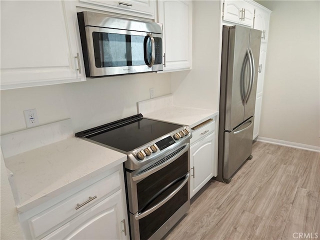 4734 Park Granada Unit 238, Calabasas, CA 91302 - kitchen featuring appliances with stainless steel finishes, light wood finished floors, white cabinetry, and light stone counters