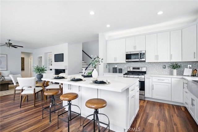 27170 Arrow Point Trl, Corona, CA 92883 - kitchen featuring appliances with stainless steel finishes, open floor plan, a breakfast bar area, white cabinetry, and a kitchen island