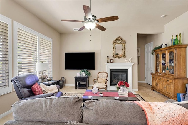 19423 Crystal Springs Ln, Apple Valley, CA 92308 - living room featuring a ceiling fan, baseboards, a glass covered fireplace, and light tile patterned floors