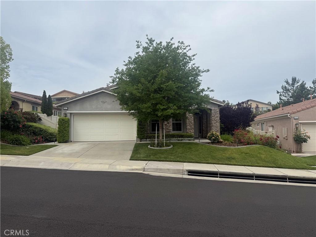 317 Calvert, Beaumont, CA 92223 - view of property hidden behind natural elements with a garage, concrete driveway, a front yard, and stone siding
