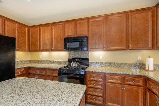 317 Calvert Park, Beaumont, CA 92223 - kitchen with black appliances, light stone countertops, and brown cabinets