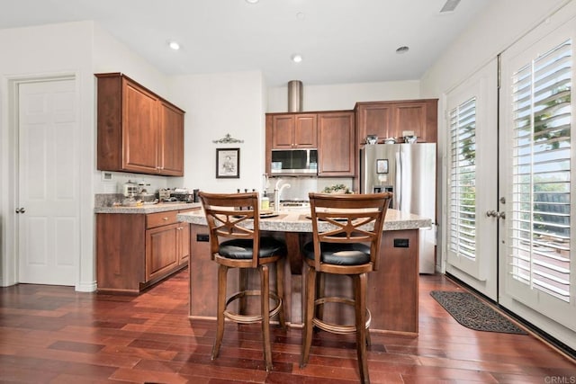 2227 Villa Verde Rd, Escondido, CA 92029 - kitchen with stainless steel microwave, dark wood-style flooring, a center island with sink, brown cabinets, and a kitchen breakfast bar