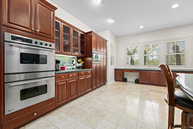2227 Villa Verde Rd, Escondido, CA 92029 - kitchen with appliances with stainless steel finishes, built in study area, tasteful backsplash, recessed lighting, and glass insert cabinets