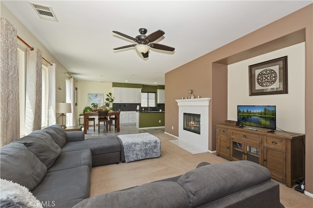 213 Caldera St, Perris, CA 92570 - living room featuring ceiling fan, light colored carpet, a fireplace with flush hearth, and baseboards