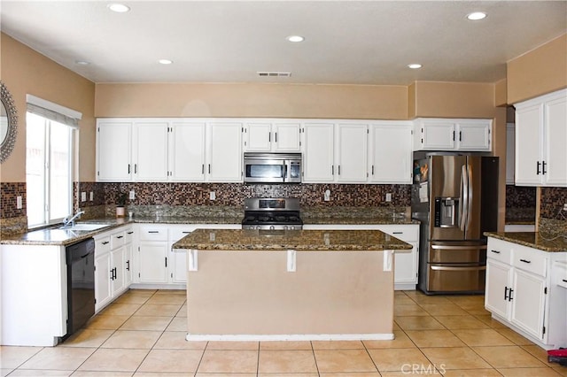 12655 Verano St, Victorville, CA 92392 - kitchen featuring appliances with stainless steel finishes, dark stone countertops, white cabinetry, a kitchen island, and tasteful backsplash