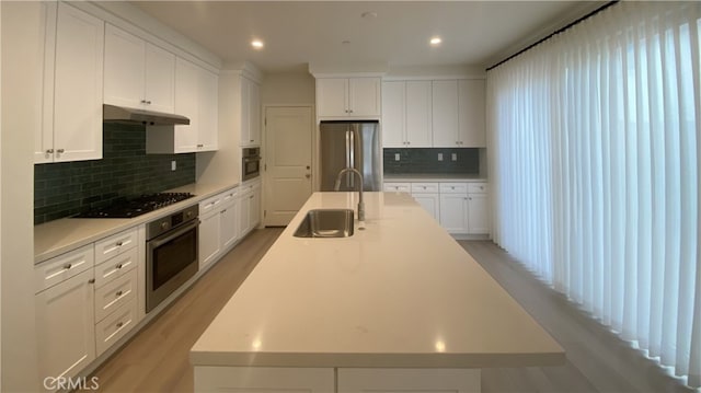 110 Sunnyside, Irvine, CA 92618 - kitchen with appliances with stainless steel finishes, a sink, an island with sink, decorative backsplash, and light countertops
