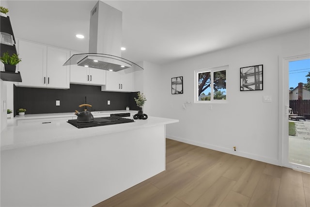 1152 W Tudor St, San Dimas, CA 91773 - kitchen with island range hood, white cabinetry, light countertops, light wood-style flooring, and a peninsula