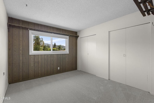 6421 Almar St, Simi Valley, CA 93063 - unfurnished bedroom with multiple closets, a textured ceiling, carpet floors, and wooden walls