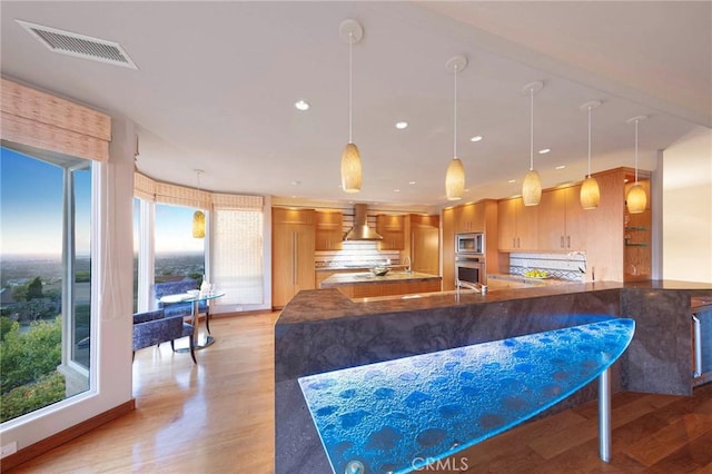 3 Harbor Ridge Dr, Newport Beach, CA 92660 - kitchen featuring wall chimney range hood, appliances with stainless steel finishes, light wood-style flooring, brown cabinets, and recessed lighting