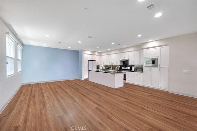 228 Borrego, Irvine, CA 92618 - kitchen with dark countertops, open floor plan, light wood-type flooring, appliances with stainless steel finishes, and white cabinets