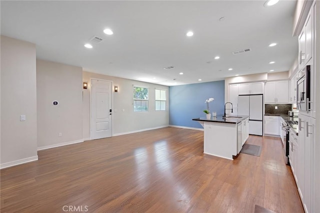 228 Borrego, Irvine, CA 92618 - kitchen with freestanding refrigerator, dark countertops, open floor plan, light wood-type flooring, and an island with sink