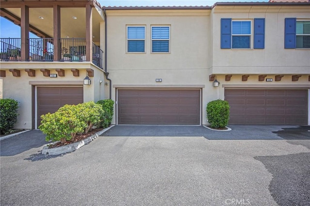 228 Borrego, Irvine, CA 92618 - view of property featuring a garage, driveway, stucco siding, and a balcony