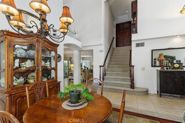 10830 Orchard View Ln, Riverside, CA 92503 - tiled dining room featuring arched walkways, stairs, a chandelier, a towering ceiling, and baseboards