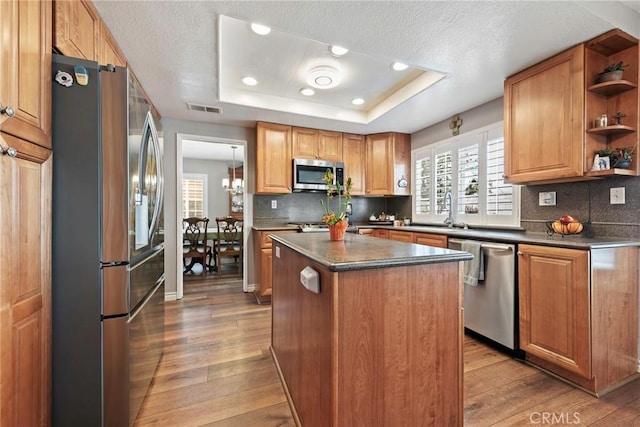 9081 Mandarin Ln, Riverside, CA 92508 - kitchen featuring stainless steel appliances, a raised ceiling, dark countertops, light wood-style flooring, and recessed lighting