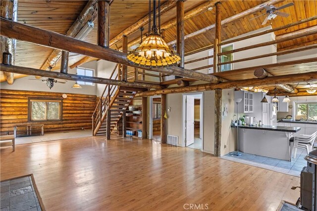 30771 Fox Ridge Ct, Tehachapi, CA 93561 - unfurnished living room featuring wooden ceiling with exposed beams, a chandelier, log walls, wood finished floors, and high vaulted ceiling