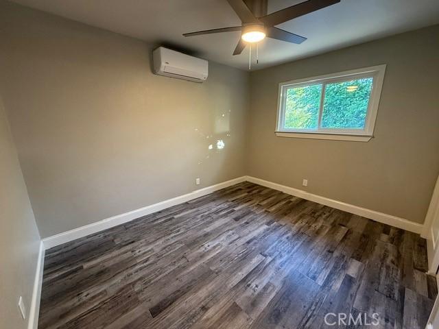 2911 Rancho Vista Dr, Lucerne, CA 95458 - empty room featuring a wall mounted AC, dark wood-style flooring, a ceiling fan, and baseboards