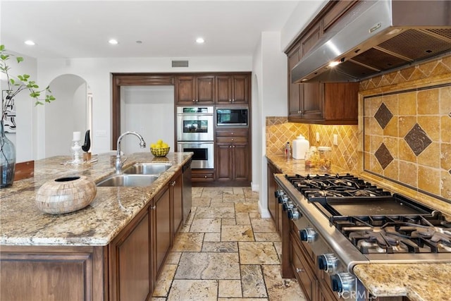 15 Basilica Pl, Ladera Ranch, CA 92694 - kitchen featuring range hood, stainless steel appliances, a sink, stone tile flooring, and arched walkways