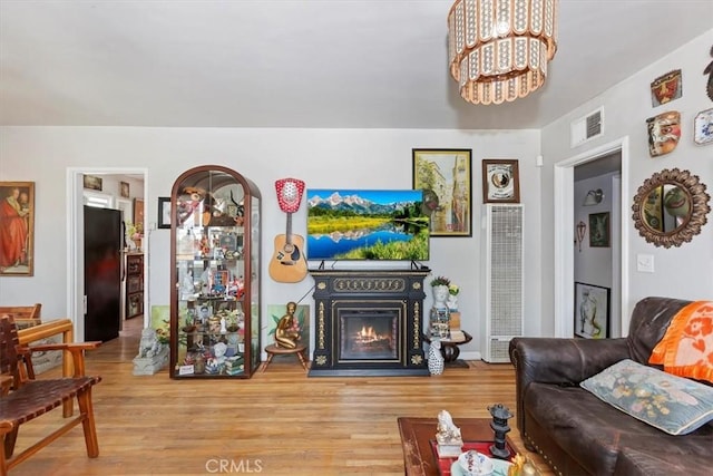 112 W Grandview Dr, Barstow, CA 92311 - living area featuring a heating unit, a lit fireplace, wood finished floors, and a chandelier