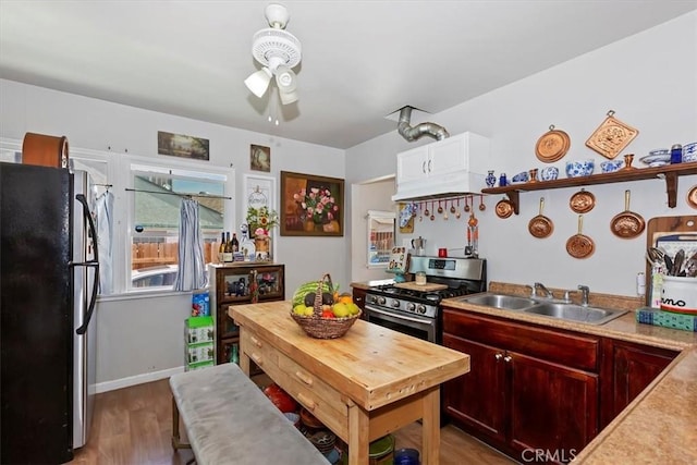 112 W Grandview Dr, Barstow, CA 92311 - kitchen featuring freestanding refrigerator, stainless steel range with gas stovetop, a sink, a ceiling fan, and wood finished floors