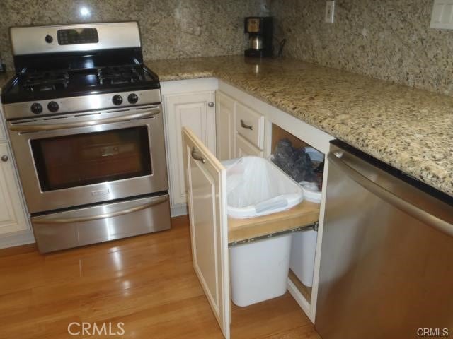 11459 Shippigan Way, Cypress, CA 90630 - kitchen with stainless steel appliances, tasteful backsplash, light wood-type flooring, white cabinetry, and light stone countertops