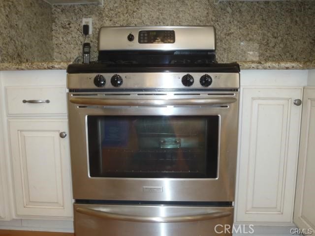 11459 Shippigan Way, Cypress, CA 90630 - kitchen view of stainless steel stove, light stone counters, and white cabinetry