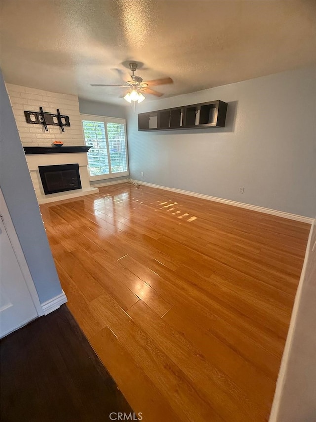 11459 Shippigan Way, Cypress, CA 90630 - unfurnished living room with wood finished floors, a ceiling fan, a brick fireplace, and a textured ceiling