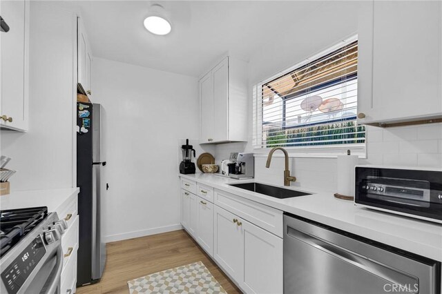 1330 N Crescent Heights Blvd Unit 12, West Hollywood, CA 90046 - kitchen featuring appliances with stainless steel finishes, a sink, light wood-type flooring, white cabinetry, and light countertops